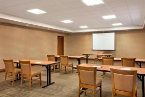 uma sala de conferências com mesas e cadeiras e um ecrã branco em Four Points by Sheraton Regina em Regina