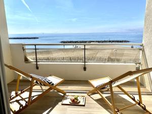 uma varanda com 2 cadeiras e vista para a praia em Appartement Elida vue mer em Palavas-les-Flots