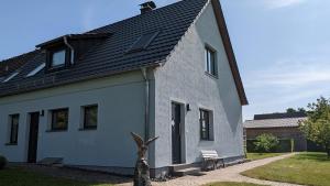 uma casa branca com um telhado preto em Ferienwohnung Am Ufer an der Müritz em Rechlin