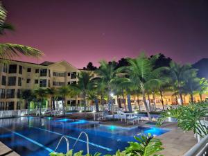 a pool at a resort at night with palm trees at Loft Condado Mangaratiba in Mangaratiba
