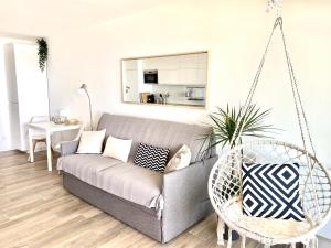 uma sala de estar com um sofá e um baloiço em Appartement Elida vue mer em Palavas-les-Flots