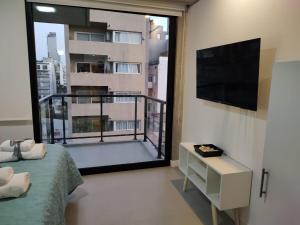 1 dormitorio con vistas a un balcón con TV en Palermo Scent 2 en Buenos Aires