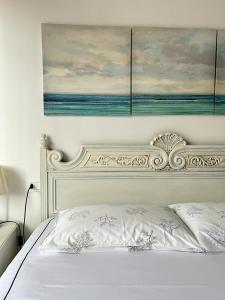 ein weißes Bett mit einem Gemälde an der Wand in der Unterkunft La casa di John in Finale Ligure