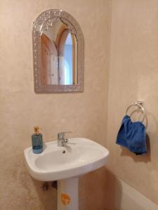 ein Badezimmer mit einem weißen Waschbecken und einem Spiegel in der Unterkunft Dar diafa samira in Mirleft
