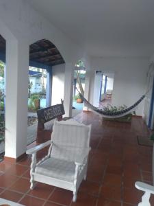 a porch with a white chair and a hammock at Pousada Chez Soleil CibrateI Itanhaém in Itanhaém