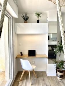 a desk in a room with a white chair and a laptop at Appartement Elida vue mer in Palavas-les-Flots
