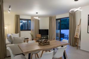 ein Wohnzimmer mit einem Holztisch und weißen Stühlen in der Unterkunft White River Villa in Nydri