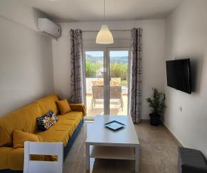 a living room with a yellow couch and a table at Kos Harmony Apartments in Kefalos