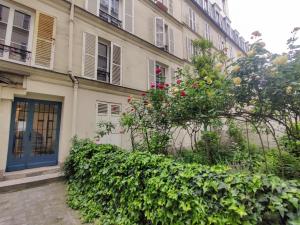 um edifício com uma porta azul e alguns arbustos em Cozy apartment with a garden view in the 17th quartier em Paris