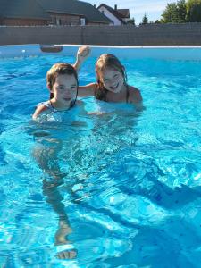 un niño y una niña nadando en una piscina en Cichy Domek Apartamenty - Podgrzewany Basen en Karwia