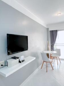 a white living room with a flat screen tv on a wall at Sea sand sun Condominiums in Rayong