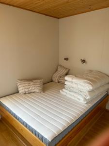 Una cama con sábanas blancas y almohadas. en Víðilundur 17, en Varmahlid