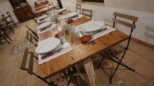 a wooden table with white plates and glasses on it at Cortijo de Vega Grande in Llerena