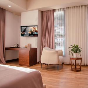 um quarto de hotel com uma cama e uma cadeira e uma televisão em Portik Hotel em Berati