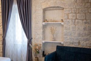 a living room with a blue couch and a stone wall at Luxury Rooms "Kaleta" in Trogir