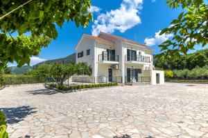 a large white house with a stone driveway at Arte villa Margarita apartment in Karavomylos