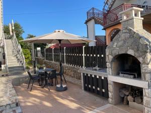 a patio with a table with an umbrella and an oven at Casa Estancia Apartment in Njivice