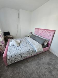 a bed with a pink head board in a bedroom at Mo's home in Tilbury