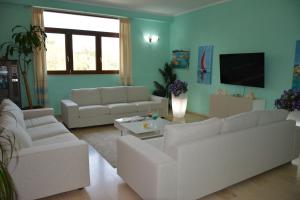 a living room with white couches and a tv at Hotel Citti in Arzachena