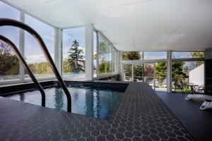 a swimming pool in a house with windows at Villa Bauhaus Silver Wellness Apartman in Siófok