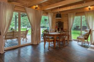 een eetkamer met een tafel en stoelen en glazen schuifdeuren bij Vila Shakti in Rudžionys