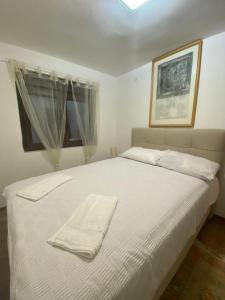 1 dormitorio con 1 cama blanca y 2 toallas en Predivna kuća na Dunavu en Krčedin