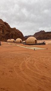three domes in a desert with a dirt field at Toleen Camp wadi rum in Wadi Rum