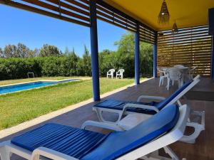 une terrasse couverte avec des chaises bleues et blanches et une piscine dans l'établissement Maison de Campagne, à Dar SaÃ¯d Ben Hajj
