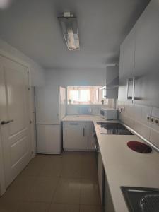 cocina blanca con fregadero y encimera en Apartamento Playa del Faro en Garrucha