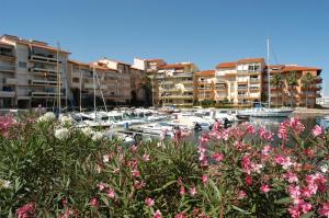 a marina with boats and buildings and pink flowers at Hotel du Port in Canet-en-Roussillon