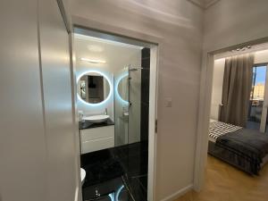 baño con espejo, lavabo y cama en Apartamenty Jagiellońskie Jurowiecka 15, en Białystok