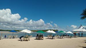 un grupo de personas sentadas bajo sombrillas en una playa en Casa da Ilha de Boipeba, en Isla de Boipeba