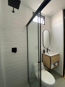 a bathroom with a toilet and a sink and a mirror at 80Cooliving Medellín in Medellín