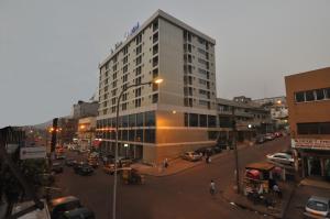 un edificio alto en una calle de la ciudad con coches en Hotel La Falaise Yaounde, en Yaoundé