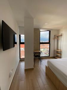 a bedroom with a bed and a table and some windows at 80Cooliving Medellín in Medellín