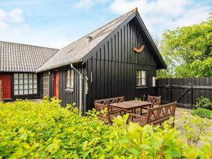 a black house with a picnic table and a fence at Holiday home Struer XXV in Struer