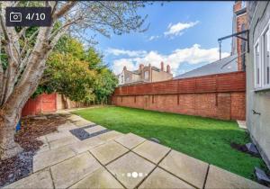 a backyard with a brick fence and a green lawn at cleethorpes seaside garden apartment in Cleethorpes