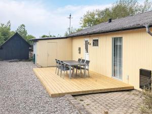 una mesa y sillas en una terraza de madera junto a un edificio en Holiday home Roslev XIX en Roslev