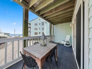 a porch with a wooden table and chairs on a balcony at Island North 14C - 2nd row stunner! Relax in comfort after your days in the sun condo in Carolina Beach