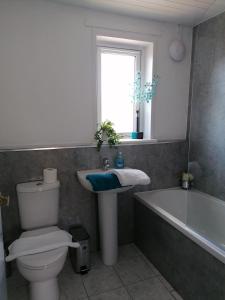 a bathroom with a toilet and a sink and a tub at Beautiful three bedroom seaside retreat in Prestonpans