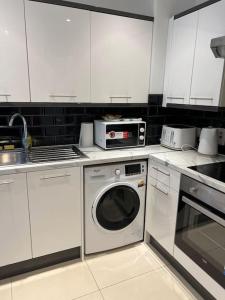 cocina con armarios blancos y lavadora en Lovely London Apartment, en Londres