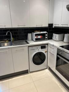 cocina con lavadora y fregadero en Lovely London Apartment, en Londres