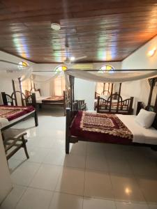a room with two beds and chairs in a room at Garden Lodge in Zanzibar City
