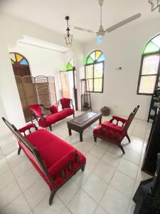 una sala de estar con muebles de color rojo y vidrieras. en Garden Lodge en Zanzíbar