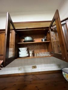 a kitchen with wooden cabinets with plates and pans at Casa Nonna Rusell in Naples