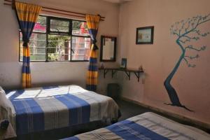 a bedroom with two beds and a tree mural on the wall at Hostel Mirador in San Cristóbal de Las Casas