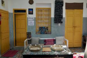 una habitación con una mesa y algunas puertas amarillas en The Madrassa, en Marrakech