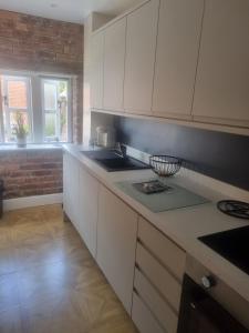 a kitchen with white cabinets and a brick wall at Grade ll listed holiday home in Llanidloes