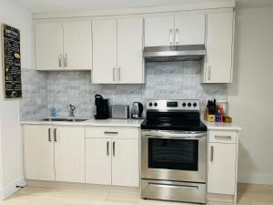 a kitchen with white cabinets and a stove top oven at New 2 bedrooms King & Queen beds Guest suite in Surrey