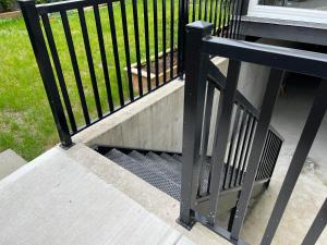 a black metal railing on a porch with grass at New 2 bedrooms King & Queen beds Guest suite in Surrey